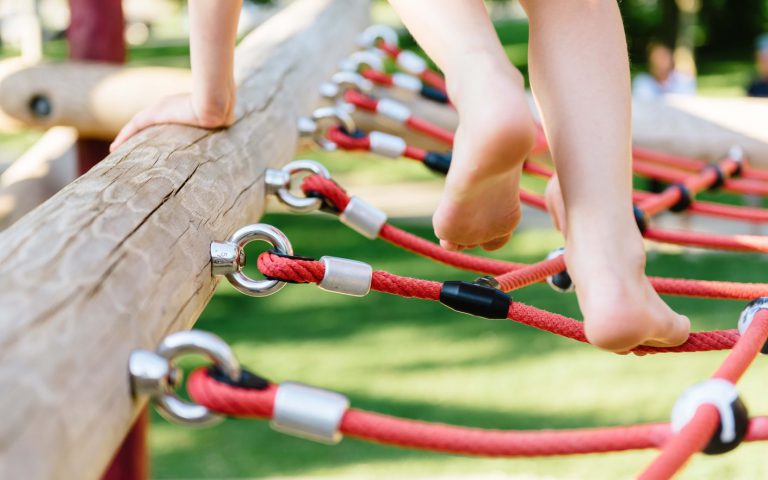 Closeup of child's feet walking across rope on an Earthscape playground