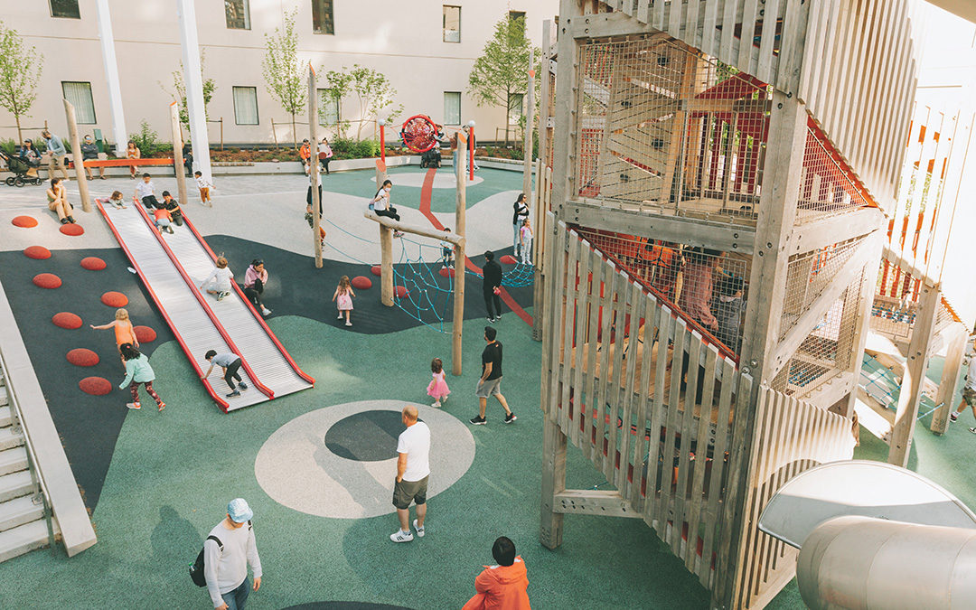 View of playground towers with climbing and tube slide with roller slide on hill