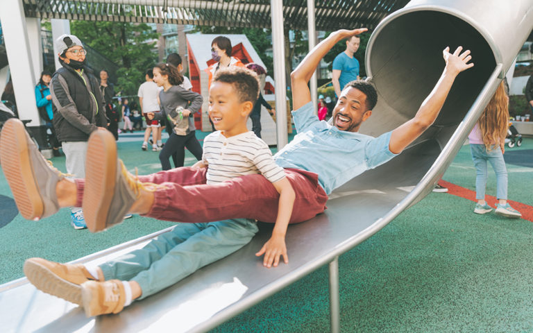 Vancouver father and son emerge from stainless steel tube slide at Smithe and Richards playground