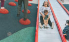 Grandmother and grandchild slide down roller slide at Vancouver playground at Smithe and Richards
