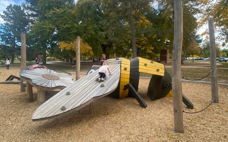Patina of play bee sculpture with kids at play in Wash Park Denver