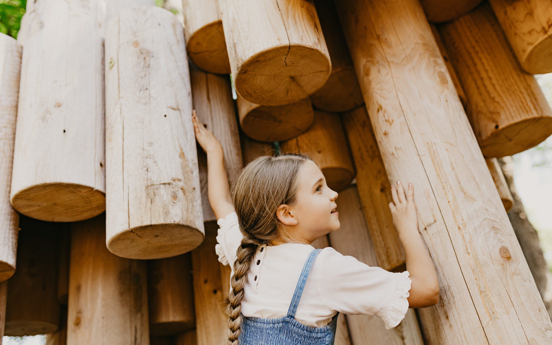 Girl touching logs beneath Moku Yama wood mountain playground by Earthscape